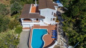 A large house with a swimming pool, a covered patio, and a white fence.