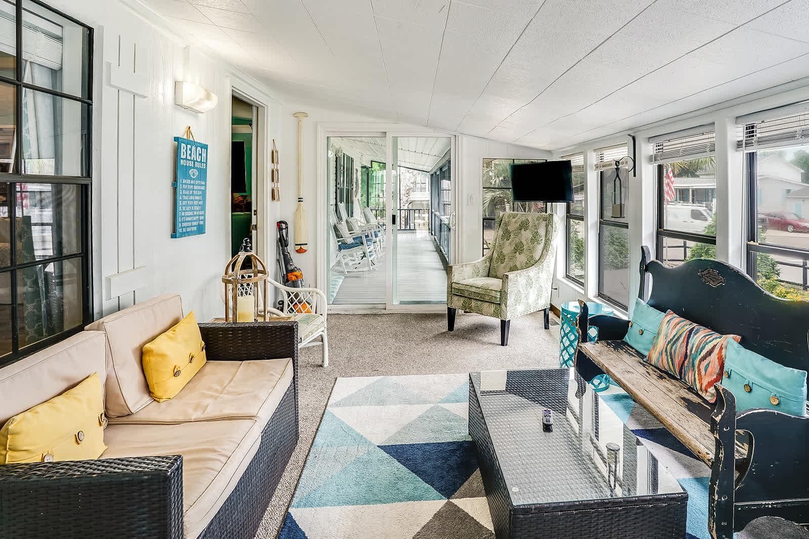 A spacious living area with a sofa, armchairs, a coffee table, and a TV.