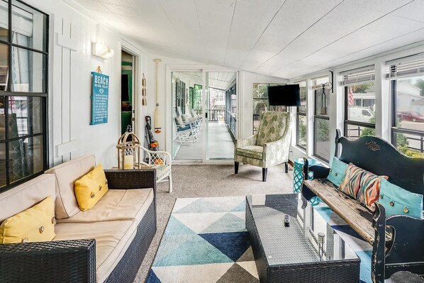 A spacious living area with a sofa, armchairs, a coffee table, and a TV.