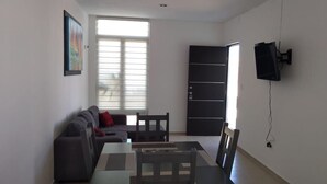 Un salon comprenant un canapé, une table basse, un téléviseur fixé au mur et un placard à portes coulissantes.