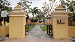 Une entrée fermée par un portail mène à un parc où un panneau indique : « Hacienda Anicabil ».