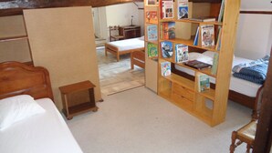 Une chambre avec une bibliothèque en bois remplie de livres, un lit en bois et une petite table de chevet en bois.