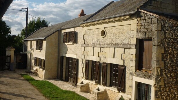 Un bâtiment en pierre doté de nombreuses fenêtres et portes, une allée pavée et une zone herbeuse.