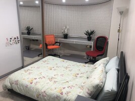 Un dormitorio con una cama, dos sillas, un escritorio y un espejo.