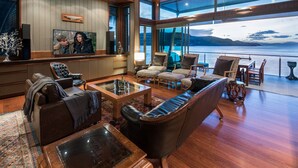 Un salon spacieux doté d’une grande télévision, de sièges confortables et offrant une vue sur l’eau.