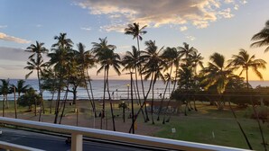 A view of a beach with palm trees and a road in the foreground. - Ocean‑View at Island Surf- Walk to Beaches, Surfing, Shops, Dining & Kalama Park (Kihei)