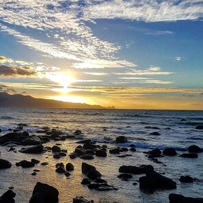 A beach with rocks and waves at sunset.