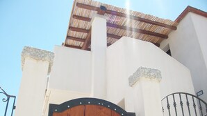 A building with a wooden gate, white walls, and a metal staircase. - Bella casa vacanze in Sardegna (Lotzorai)