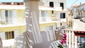 A balcony with a table and chairs, a potted orchid, and a view of buildings in the background. - Bella casa vacanze in Sardegna (Lotzorai)