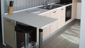 A modern kitchen with light wood cabinets, a white countertop, a sink, a stove, and a dishwasher. - Bella casa vacanze in Sardegna (Lotzorai)