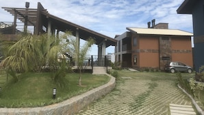 A modern building with a covered walkway, a car parked nearby, and a well-maintained lawn. - House with 2 bedrooms in a condominium. (Praia da Gamboa)