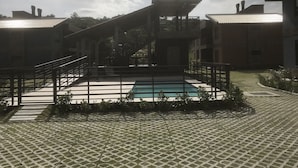 A courtyard with a swimming pool, a staircase, and surrounding buildings. - House with 2 bedrooms in a condominium. (Praia da Gamboa)