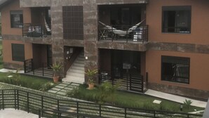 A modern two-story building with balconies, a staircase, and a garden area. - House with 2 bedrooms in a condominium. (Praia da Gamboa)