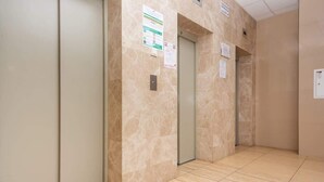 A hallway with three elevator doors, each with a sign above. - Bright Apartment in the Center | Balcony and 270 m to the Metro (Warszawa)