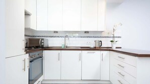 A modern kitchen with white cabinets, a built-in oven, a microwave, and a coffee maker. - Bright Apartment in the Center | Balcony and 270 m to the Metro (Warszawa)