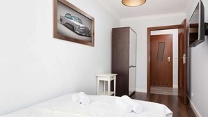 A hotel room with a bed, a small table, a wardrobe, a door, and a TV mounted on the wall. - Bright Apartment in the Center | Balcony and 270 m to the Metro (Warszawa)