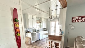 A kitchen with white cabinets, a wooden ceiling, and a red surfboard decoration. - PRIVATE LAKEFRONT + DOCK Bring your boat,  Hot Tub, Kayaks, Paddleboards (Montverde)