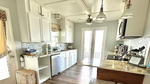 A kitchen with white cabinets, a wooden floor, a built-in dishwasher, and a bar area with stools. - PRIVATE LAKEFRONT + DOCK Bring your boat,  Hot Tub, Kayaks, Paddleboards (Montverde)