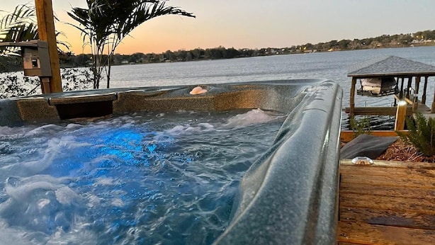 A hot tub with a wooden deck and a view of a body of water. - PRIVATE LAKEFRONT + DOCK Bring your boat,  Hot Tub, Kayaks, Paddleboards (Montverde)