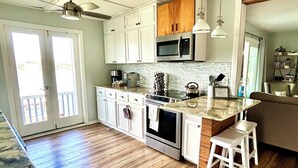 A spacious kitchen with white cabinets, a microwave, an oven, and a large island with bar stools. - PRIVATE LAKEFRONT + DOCK Bring your boat,  Hot Tub, Kayaks, Paddleboards (Montverde)