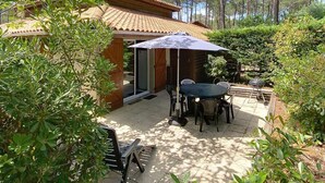 Un espace patio aménagé avec une table et des chaises, un barbecue et un coin salon abrité.