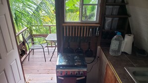 Una cocina con estufa, ollas y ventana con vista a follaje.