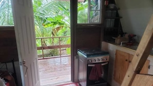 Cocina con estufa a gas, alacenas de madera y vista a un jardín por un ventanal.
