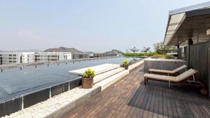 A rooftop terrace with a flat roof, seating area, and a view of distant buildings. - Hua Hin Condo 200m near beach (Nong Kae)