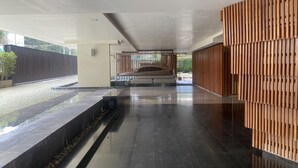 A spacious lobby with a modern design, featuring a reflective floor, a seating area with benches, and a wooden decorative wall. - Hua Hin Condo 200m near beach (Nong Kae)