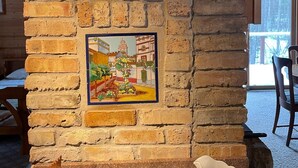 A rustic brick wall with two framed paintings depicting rural scenes. - Beautiful Cabin with Gorgeous Riverbend View. Great for relaxation and fishing! (Branch Township)