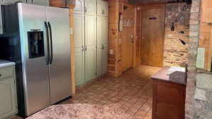 A kitchen with a stainless steel refrigerator, light green cabinets, a wooden ceiling, and a stone wall. - Beautiful Cabin with Gorgeous Riverbend View. Great for relaxation and fishing! (Branch Township)