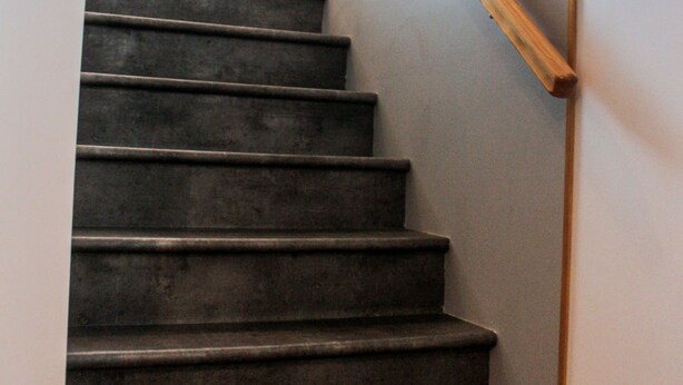 Eine Treppe mit dunklen Stufen und einem Holnlauf.