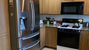 A kitchen with wooden cabinets, a stainless steel refrigerator, a microwave, and a stove. - Tranquil 3BR, 2BA Condo at Indian Palms - near Coachella (Indio)