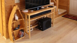 Een houten interieur met een televisie op een houten standaard, een trap en een bord met de tekst 'Don't Wake the Bear'.