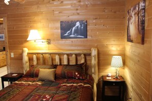 Een houten slaapkamer met een bed, twee nachtkastjes en wandlampen.