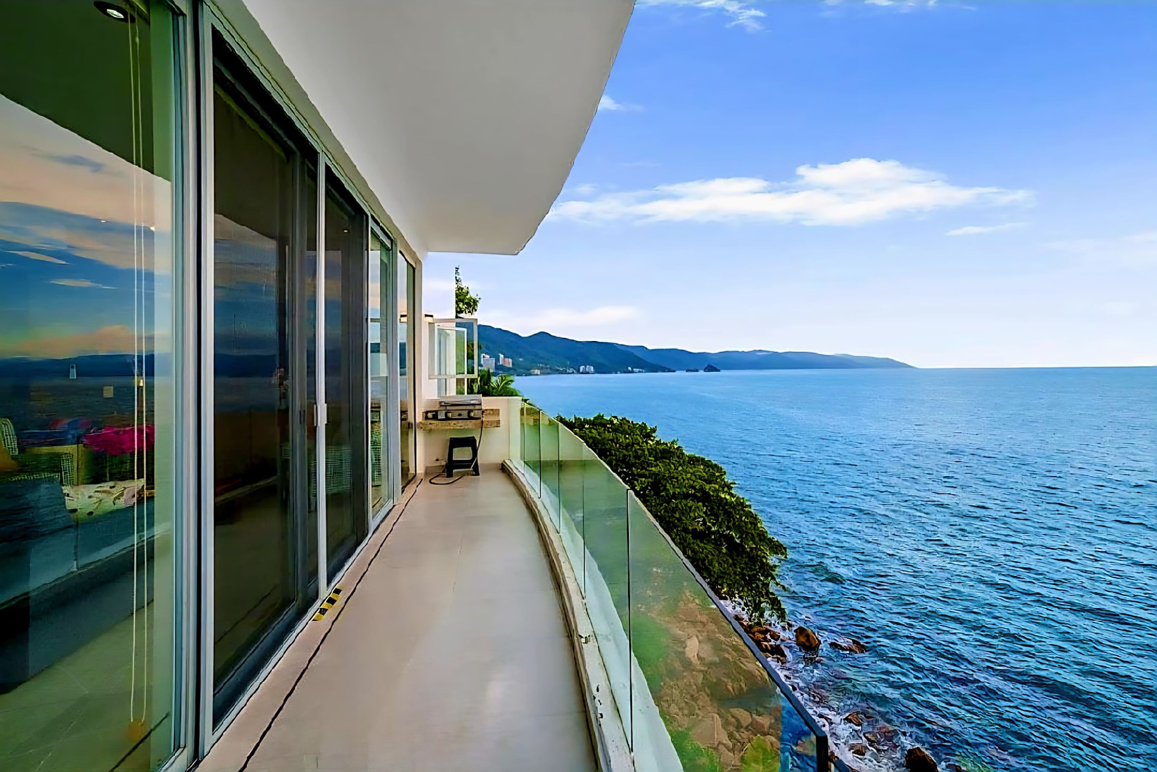 A balcony with a view of the sea and distant mountains.