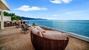 A balcony with a wicker chair and cushions, overlooking a body of water with a clear sky. - Exclusive Penthouse Oceanfront, small Condominium complex (Conchas Chinas)