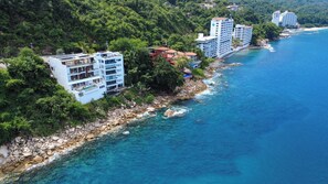 Un hôtel situé sur la côte, composé de plusieurs bâtiments, avec un rivage rocheux et une eau d’un bleu cristallin.