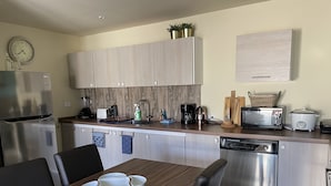 A modern kitchen with stainless steel appliances, wooden cabinets, and a dining area with a wooden table and chairs.