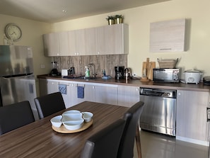 A modern kitchen with stainless steel appliances, wooden cabinets, and a dining area with a wooden table and chairs.