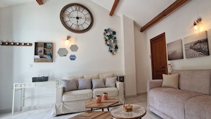 A living room with a sofa, a coffee table, a clock, and wall art.
