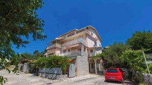 A two-story house with a balcony, a stone wall, and a red car parked in front. - Holiday apartment mit Terrasse und Klimaanlage (Dramalj)