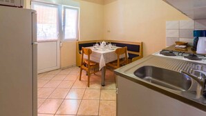 A compact kitchen with a dining table set for four, a refrigerator, a stove, and a sink. - Holiday apartment mit Terrasse und Klimaanlage (Dramalj)