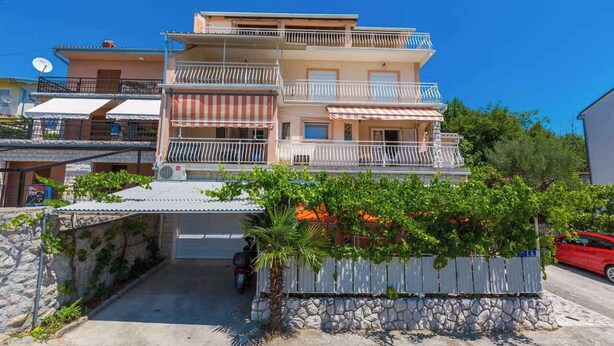 A multi-story residential building with balconies, a stone wall, and a parked car. - Holiday apartment mit Terrasse und Klimaanlage (Dramalj)