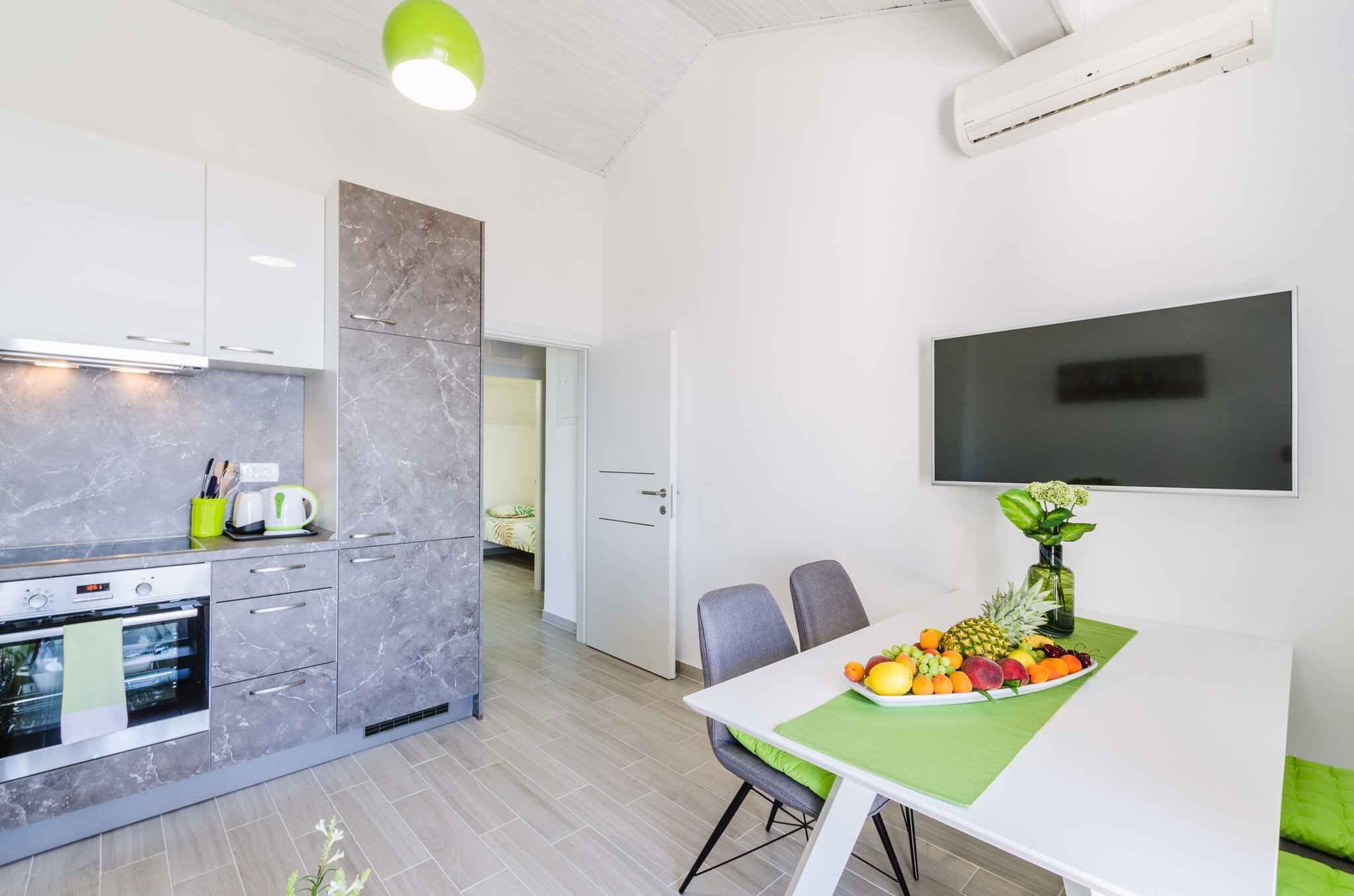 A modern kitchen with marble countertops, a built-in oven, and a dining area with a table set for two.