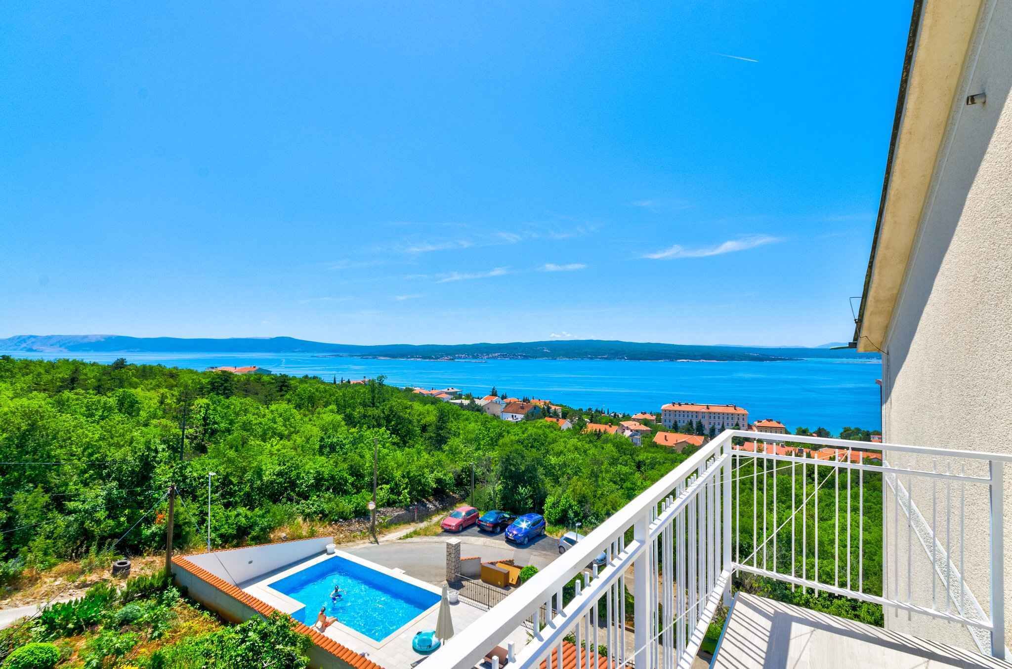 Un balcón con vistas a una piscina y un paisaje costero.