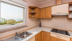 A kitchen with a window, wooden cabinets, a sink, and a stove.