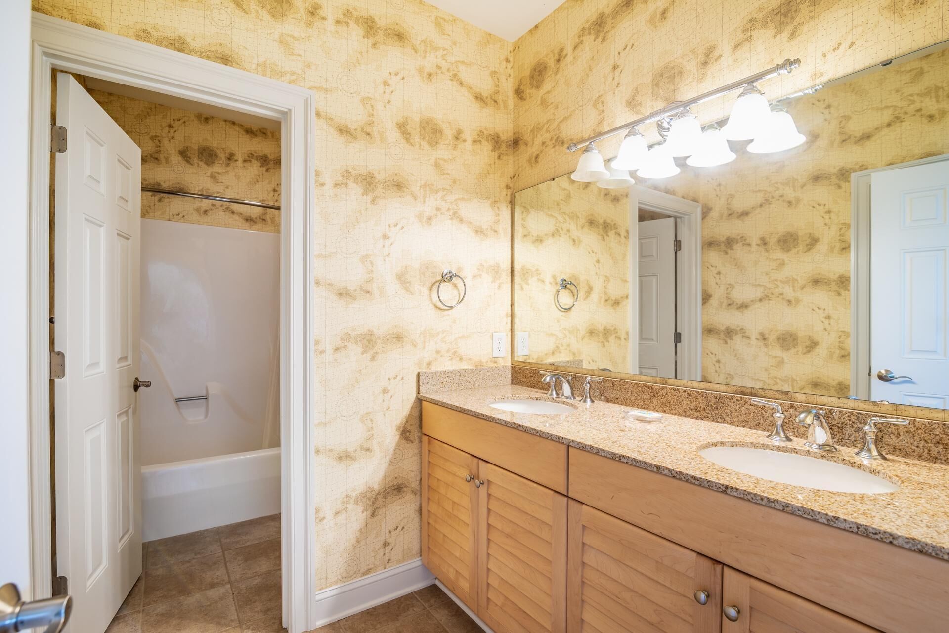 A bathroom with two sinks, a mirror, and a shower.