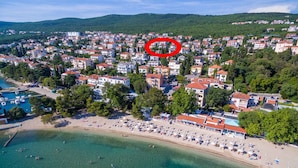An aerial view of a coastal town with a beach, houses, and a marina.