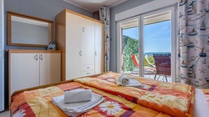 A bedroom with a bed, a wardrobe, and a balcony with a view.
